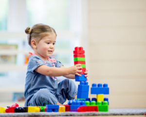 Montessori child engaging with practical life materials to improve hand-eye coordination.